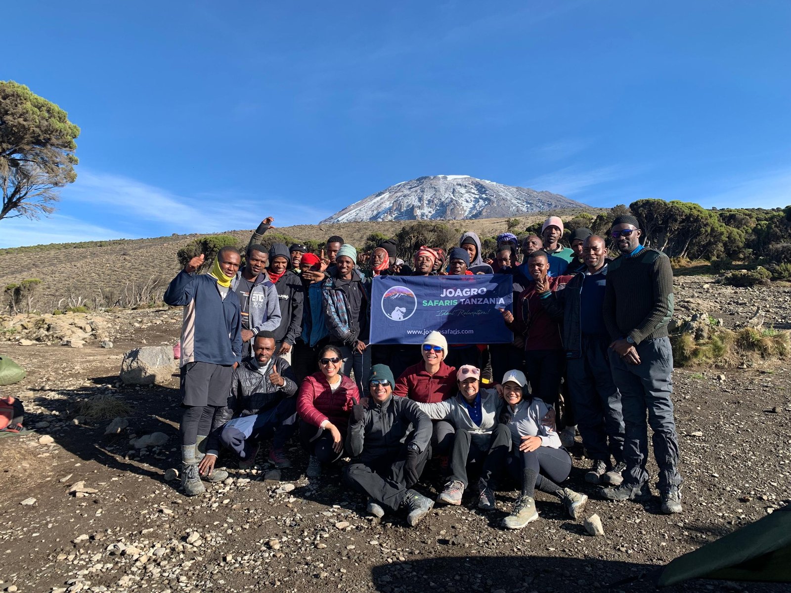 Climbers ascending Mount Kilimanjaro with summit glaciers visible above the clouds